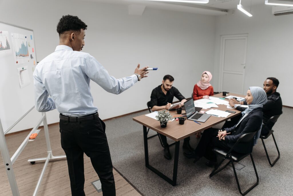 five people sitting around a table in a meeting